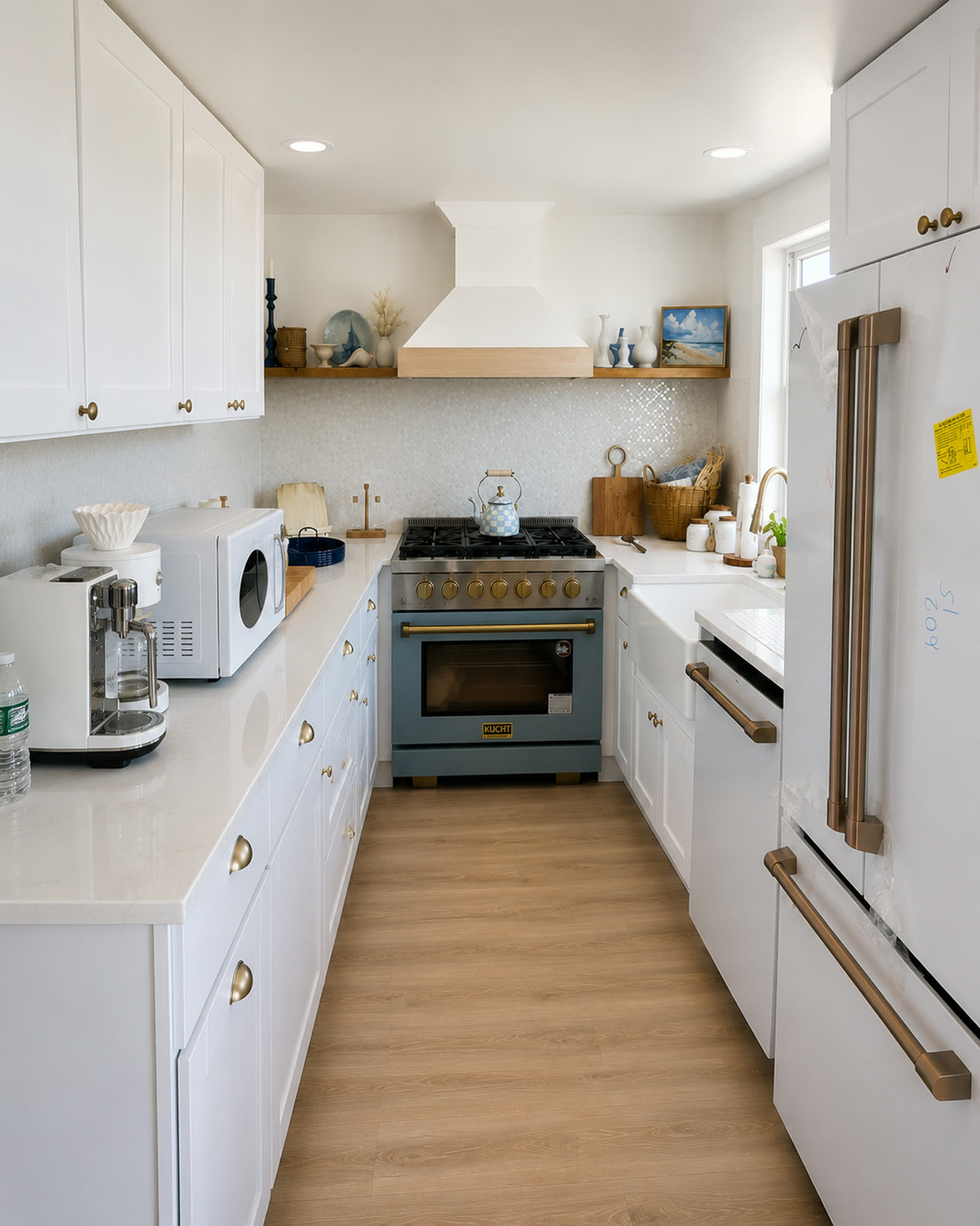 Completed kitchen renovation with white cabinetry, quartz countertops, blue range and brass hardware