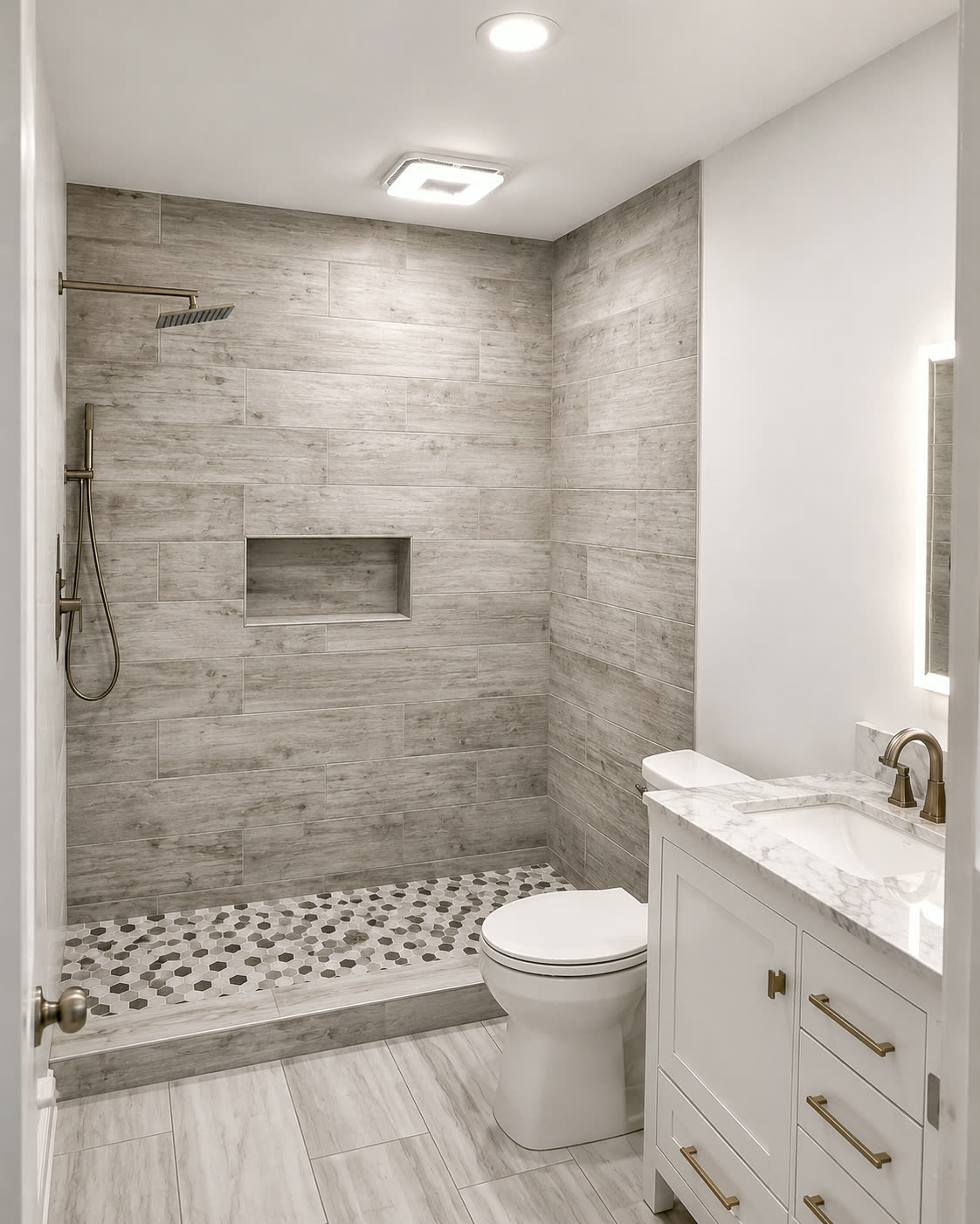 Completed bathroom renovation with tiled walk-in shower, marble-top vanity and brushed gold fixtures